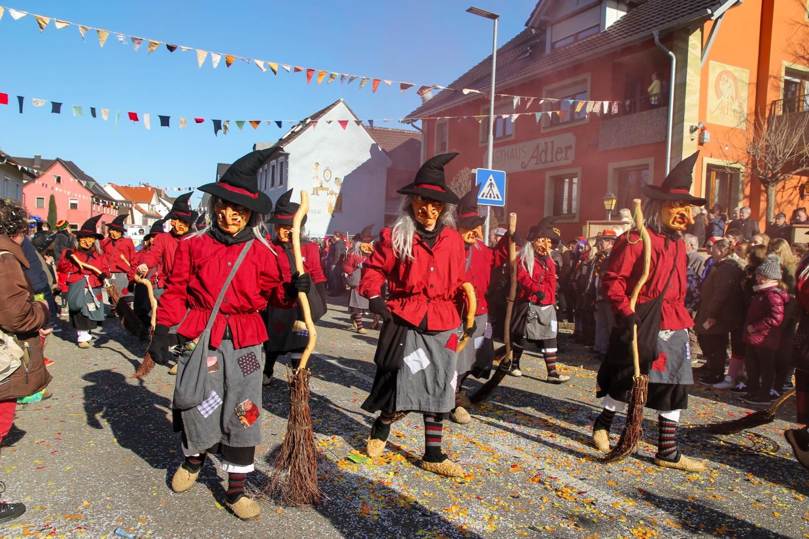 Balthasarhexen im roten Hemd mit schwarzem Rock und grauer Schürze und schwarzem Hexenhut beim Fasentzumzug durch Rusts Straßench 
