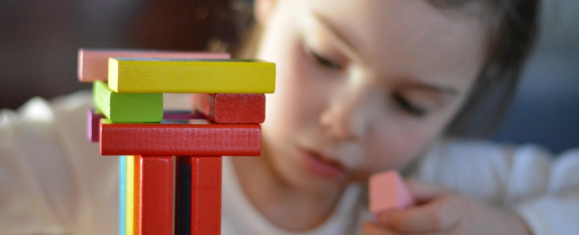 Ein Mädchen spielt mit bunten Holzbauklötzen Ein Mädchen spielt mit bunten Holzbauklötzen