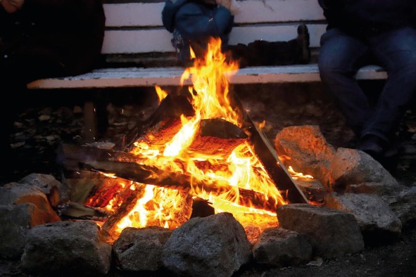 Ein großes Lagerfeuer, im Hintergrund sitzt jemand Ein großes Lagerfeuer, im Hintergrund sitzt jemand