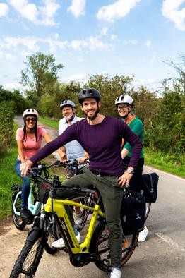 Stadtradeln Vier Menschen unterschiedlichen Alters und Geschlechts stehen auf ihren E-Bikes und lachen in die Kamera