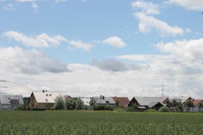 Häuser am Ortsrand Häuser am Ortsrand von Rust, davor eine Wiese, im Hintergrund ein hellblauer Himmel mit weißen Wolken