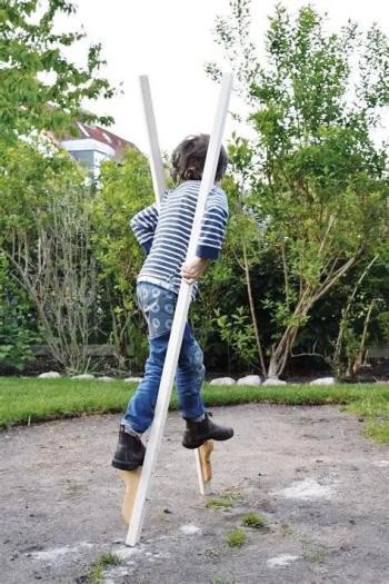 Kind in gestreiftem Pullover, Jeans und festen Schuhen läuft auf Stelzen Kind in gestreiftem Pullover, Jeans und festen Schuhen läuft auf Stelzen