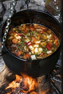Gemüsesuppe auf dem Feuer Eisentopf auf Lagerfeuer, in dem eine bunte Gemüsesuppe kocht