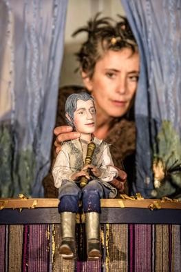 Die Zauberflöte Zwei große Puppen, Mann und Frau, haben vor sich in den Armen sechs kleine Babypuppen