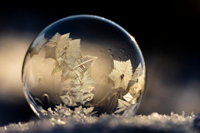 Winterabenteuer Makroaufnahme einer Wasserkugel auf Schnee zeigt Eiskristalle en detail